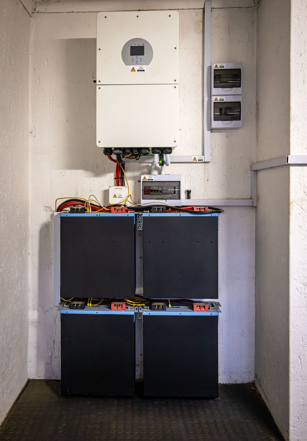 Wall-mounted solar inverter above a stack of home battery units